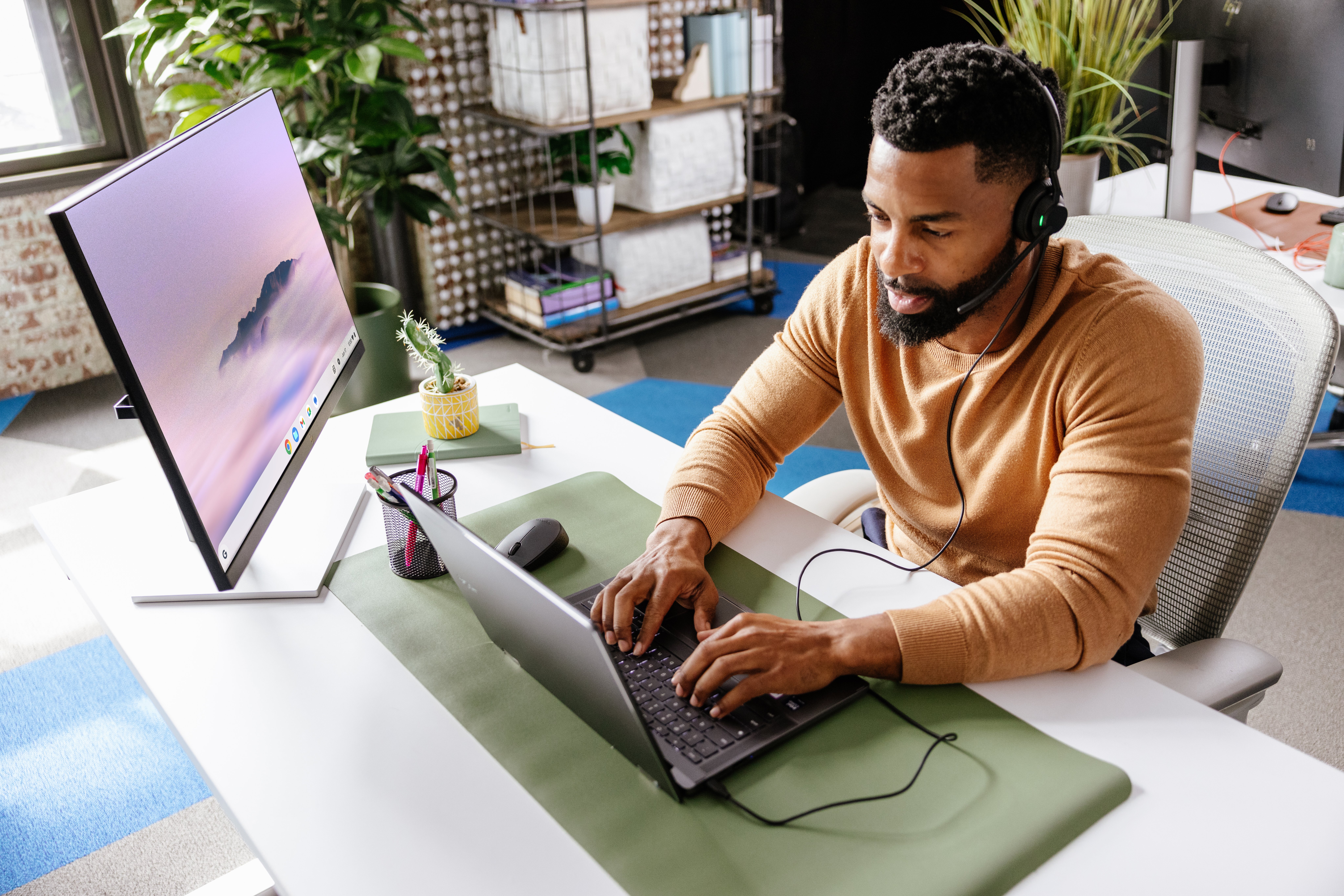 A young professional male works from a Chromebook and secondary monitor