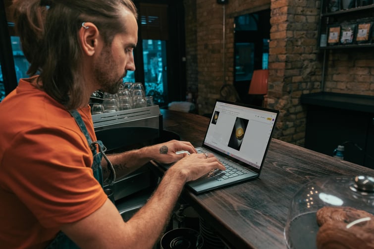 Hip young man uses a Chromebook to manage his coffeeshop