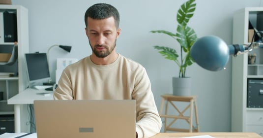 Serious businessperson typing on laptop computer in an indoor office setting