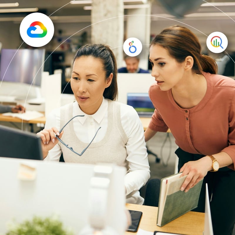 Two women review information on a desktop screen in an office setting