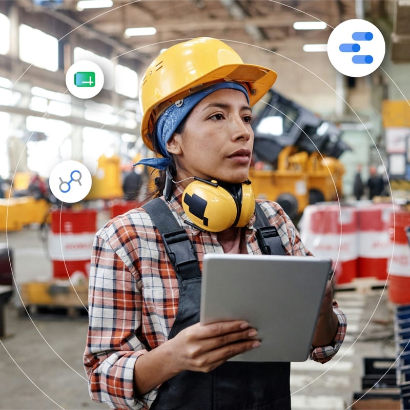 A woman wearing a hard hat uses a table in a manufacturing setting