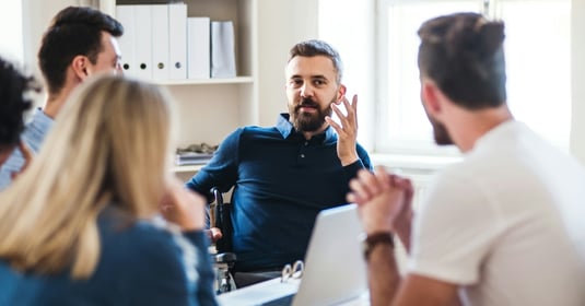 Office worker talks to a group of coworkers in an office setting